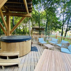 Hébergement insolite en Bretagne : cabane en bois avec jacuzzi et coin salon en extérieur.