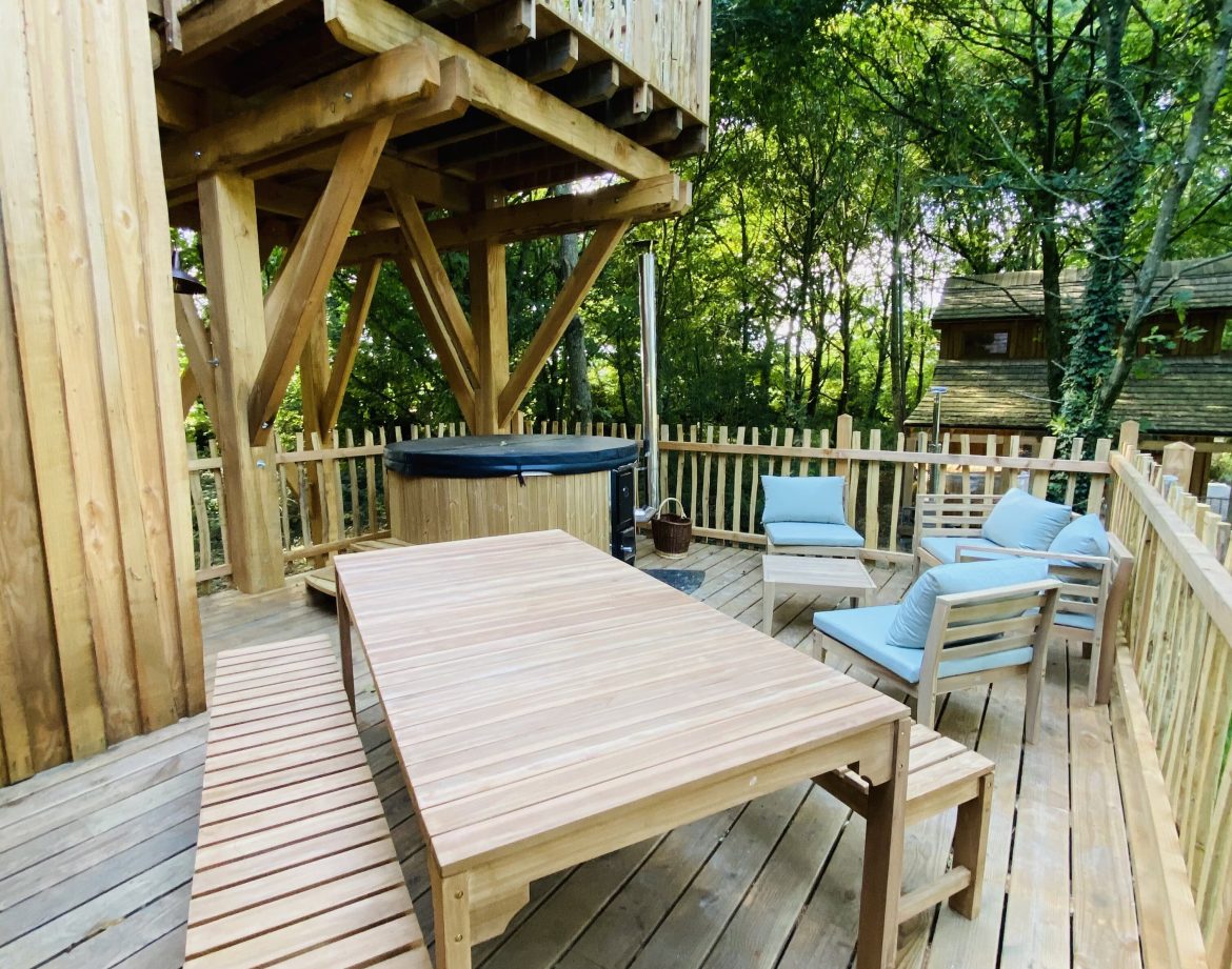Cabane perchée en Bretagne avec terrasse en bois et jacuzzi extérieur.