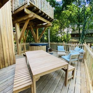 Cabane perchée en Bretagne avec terrasse en bois et jacuzzi extérieur.