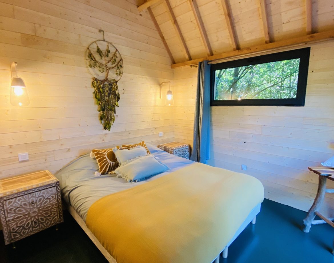 Chalet en bois en Bretagne, avec un lit douillet et des murs en bois clair.