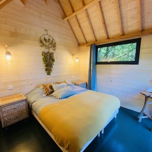 Chalet en bois en Bretagne, avec un lit douillet et des murs en bois clair.