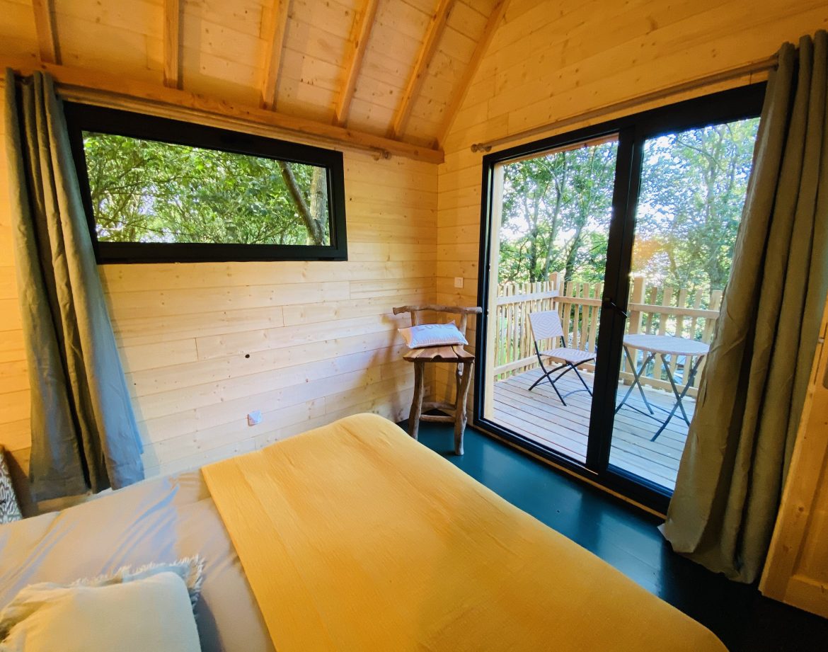 Cabane en bois en Bretagne, avec vue sur la nature et terrasse ensoleillée.
