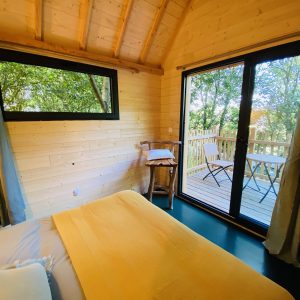 Cabane en bois en Bretagne, avec vue sur la nature et terrasse ensoleillée.