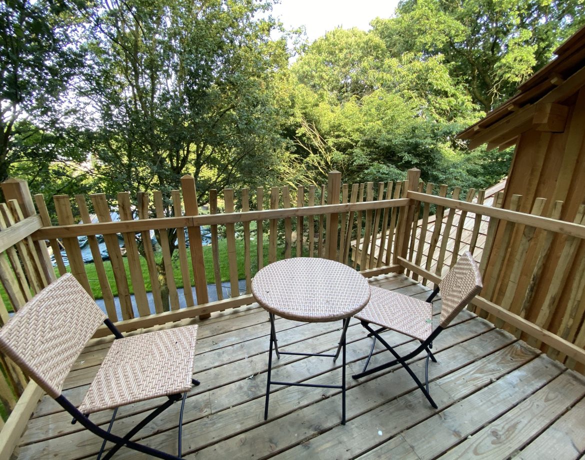 Terrasse en bois avec deux chaises et une table, hébergement insolite en Bretagne.
