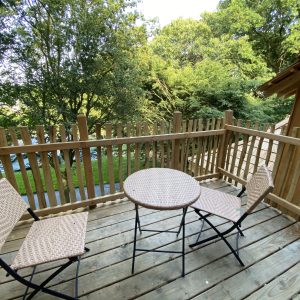 Terrasse en bois avec deux chaises et une table, hébergement insolite en Bretagne.