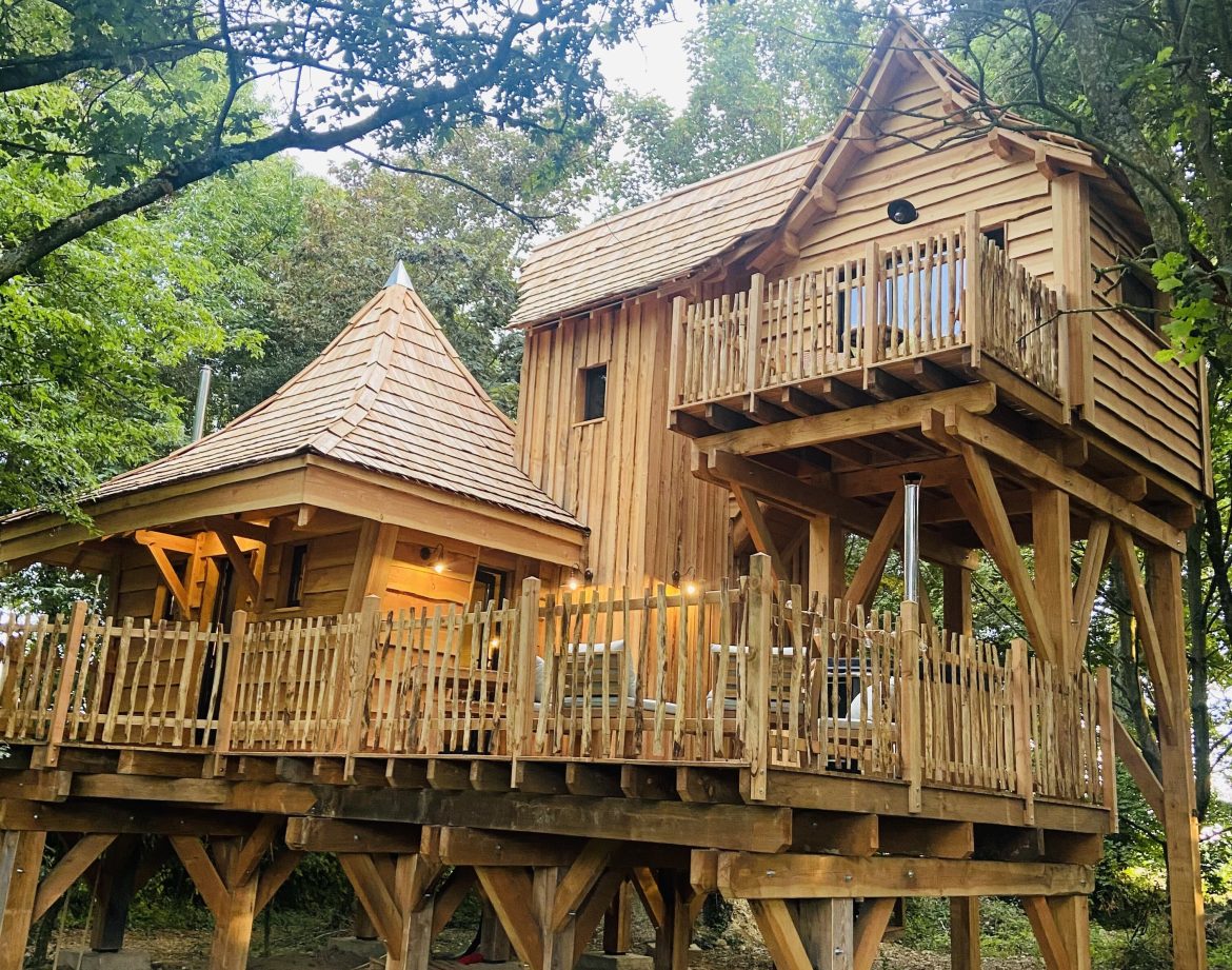 Cabane dans les arbres en Bretagne, avec balcons en bois et toiture en ardoise.
