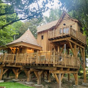 Cabane dans les arbres en Bretagne, avec balcons en bois et toiture en ardoise.