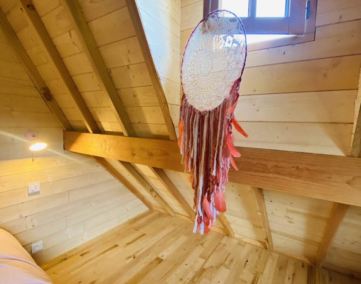 Chalet en bois en Bretagne, avec un plafond en poutres et un attrape-rêves coloré.