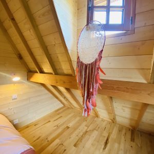 Chalet en bois en Bretagne, avec un plafond en poutres et un attrape-rêves coloré.