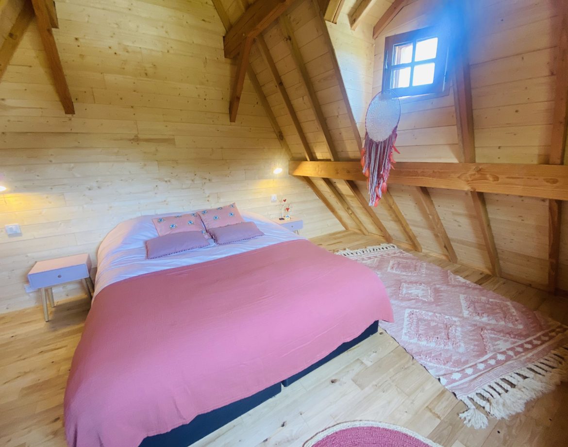 Chalet en bois en Bretagne, avec un lit douillet et des poutres apparentes.