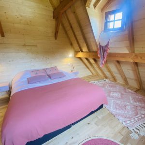 Chalet en bois en Bretagne, avec un lit douillet et des poutres apparentes.