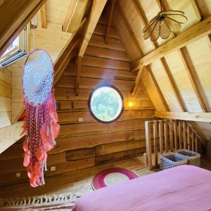 Chalet en bois en Bretagne, avec un plafond en poutres et une fenêtre ronde.