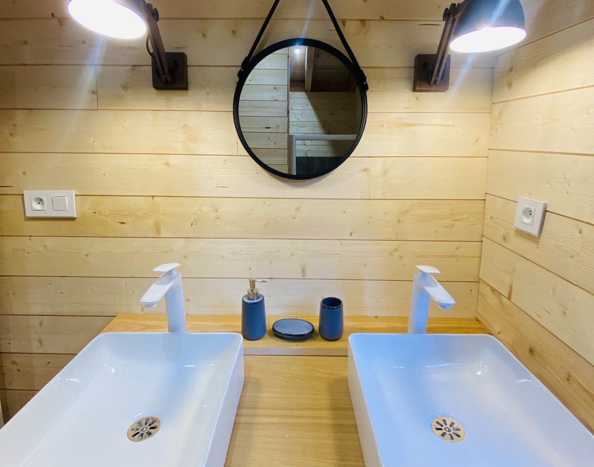 Salle de bain dun hébergement insolite en Bretagne, avec deux lavabos modernes.