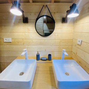 Salle de bain dun hébergement insolite en Bretagne, avec deux lavabos modernes.
