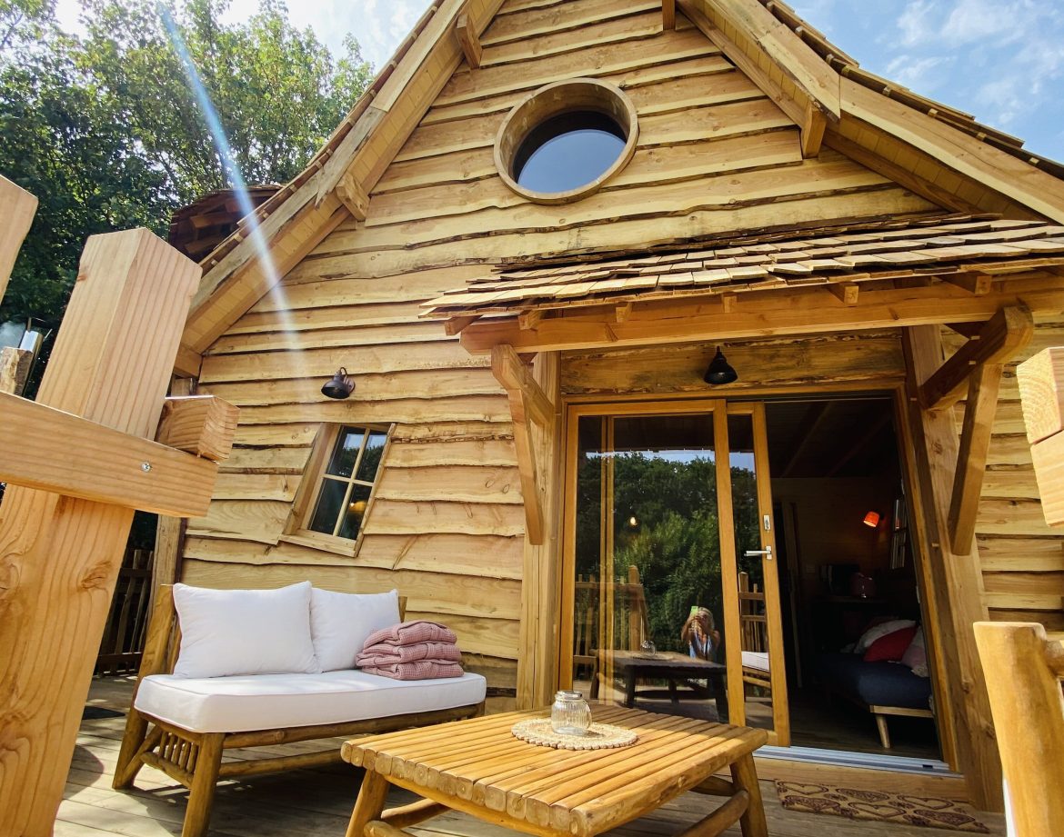 Cabane en bois en Bretagne, avec terrasse ensoleillée et vue sur la nature.