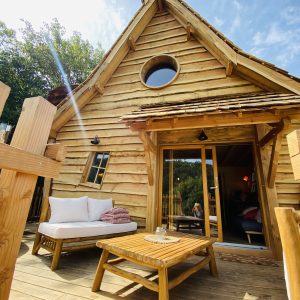 Cabane en bois en Bretagne, avec terrasse ensoleillée et vue sur la nature.