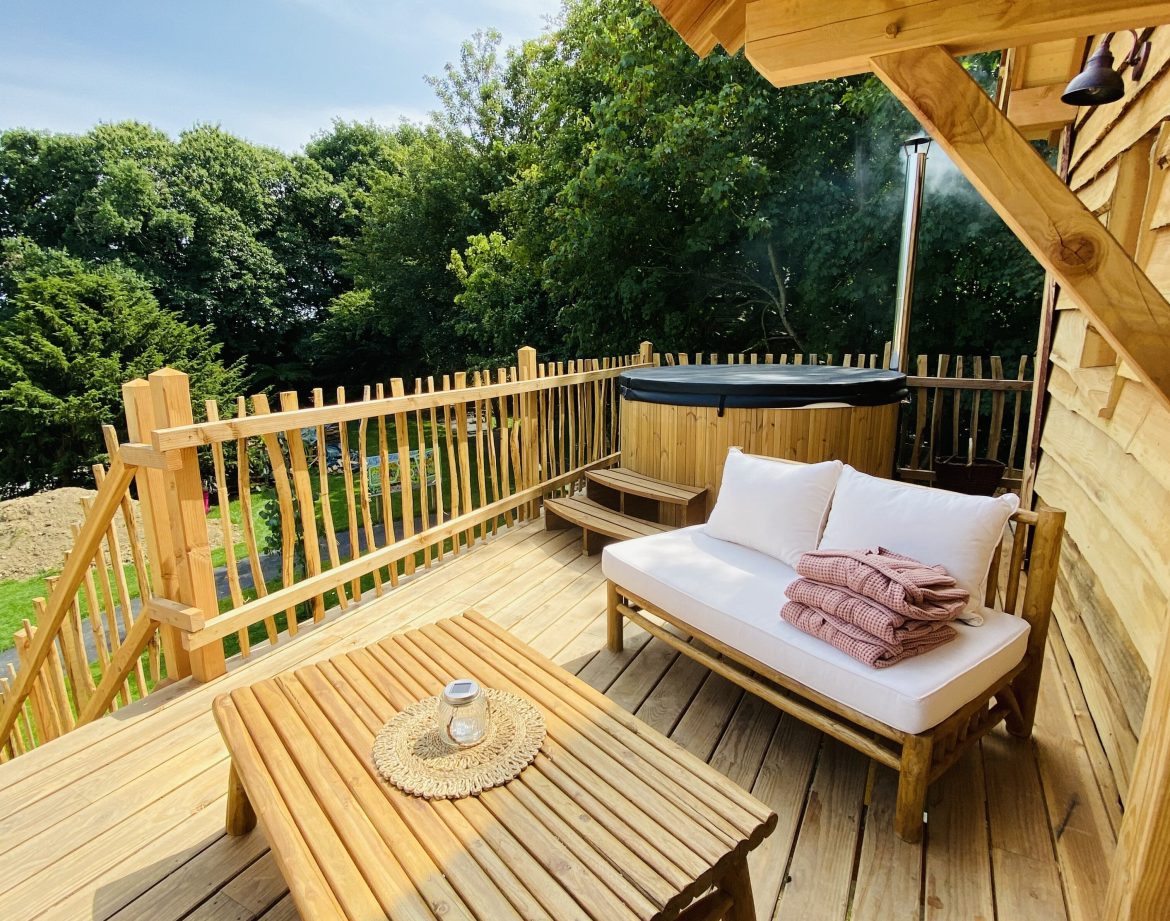 Cabane en bois en Bretagne avec terrasse en bois et jacuzzi extérieur.