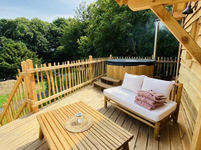 Cabane en bois en Bretagne avec terrasse en bois et jacuzzi extérieur.