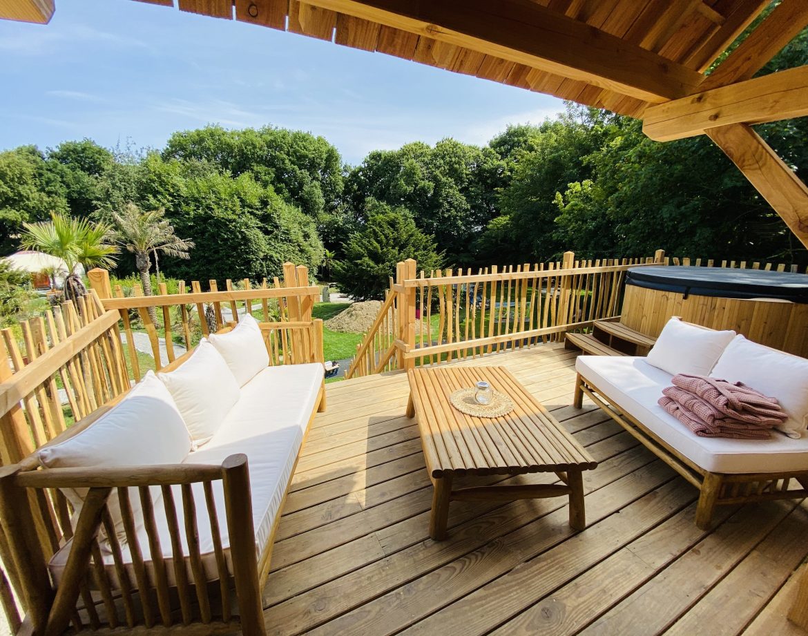 Hébergement insolite en Bretagne : terrasse en bois avec vue sur la verdure et jacuzzi.