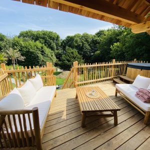 Hébergement insolite en Bretagne : terrasse en bois avec vue sur la verdure et jacuzzi.