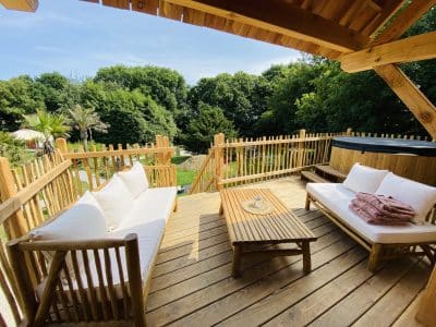 Hébergement insolite en Bretagne : terrasse en bois avec vue sur la verdure et jacuzzi.