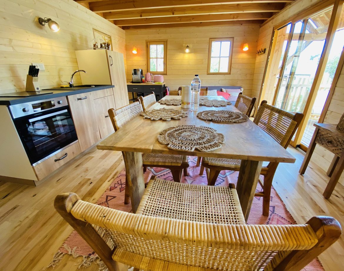 Cabane en bois en Bretagne, intérieur chaleureux avec table en bois et cuisine équipée.