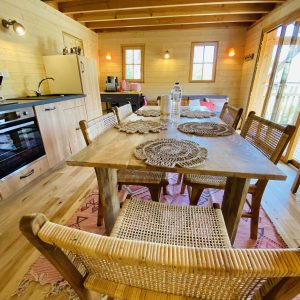 Cabane en bois en Bretagne, intérieur chaleureux avec table en bois et cuisine équipée.