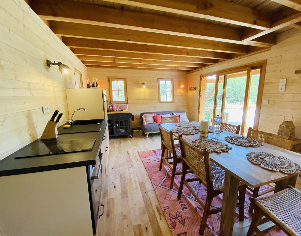 Cabane en bois en Bretagne, avec cuisine ouverte et décoration chaleureuse.