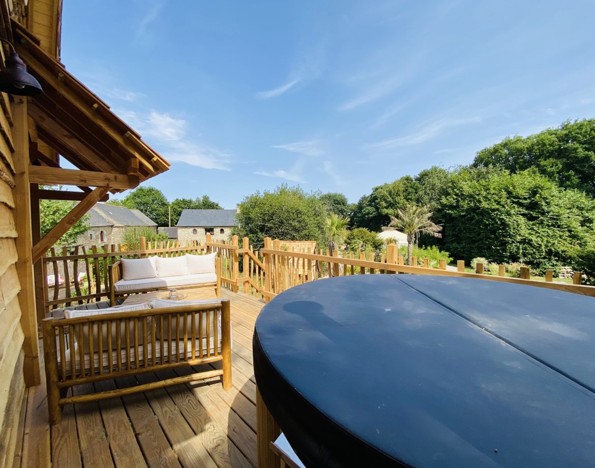 Hébergement insolite en Bretagne : cabane en bois avec terrasse et jacuzzi.
