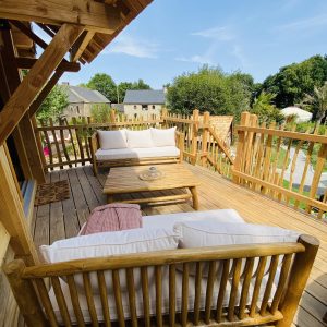 Cabane en bois en Bretagne avec terrasse ensoleillée et mobilier confortable.