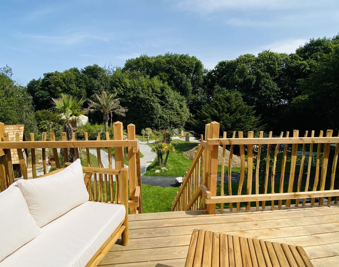Cabane en bois en Bretagne, avec vue sur un jardin verdoyant et des palmiers.