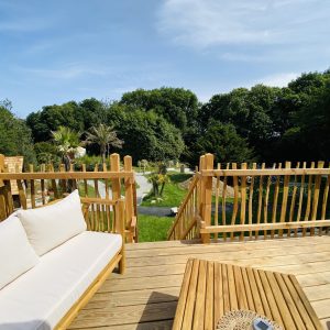 Cabane en bois en Bretagne, avec vue sur un jardin verdoyant et des palmiers.