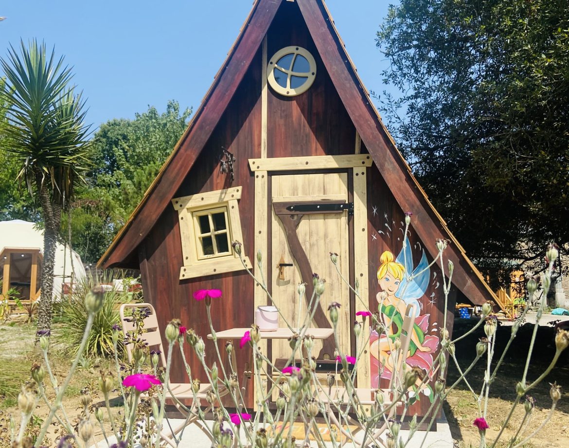 Cabane en bois en Bretagne, avec une porte décorée et des fleurs colorées.