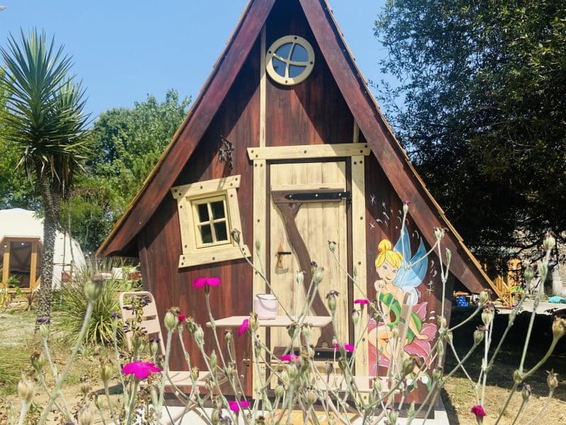 Cabane en bois en Bretagne, avec une porte décorée et des fleurs colorées.