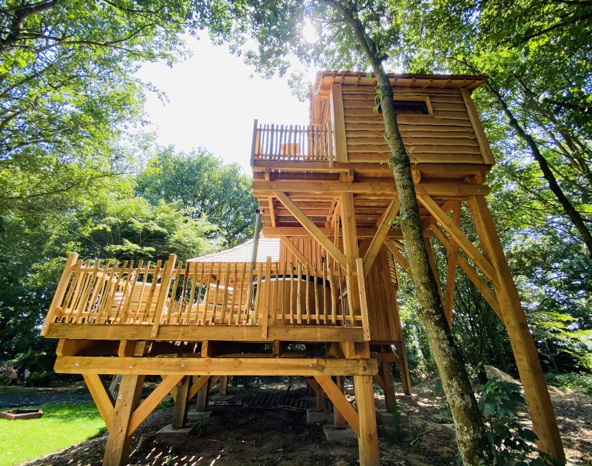 Cabane dans les arbres en Bretagne, perchée avec une terrasse en bois spacieuse.