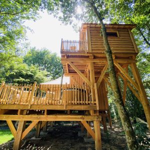 Cabane dans les arbres en Bretagne, perchée avec une terrasse en bois spacieuse.