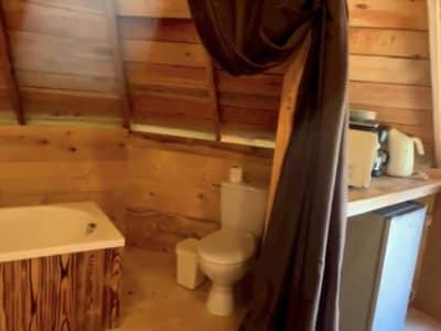 Hébergement insolite en Midi-Pyrénées, intérieur en bois avec baignoire et kitchenette.