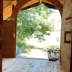 Cabane en bois avec grande baie vitrée, vue sur la nature verdoyante.