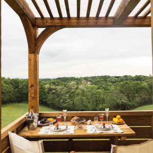 Hébergement insolite en Aquitaine : terrasse en bois avec vue sur la nature verdoyante.