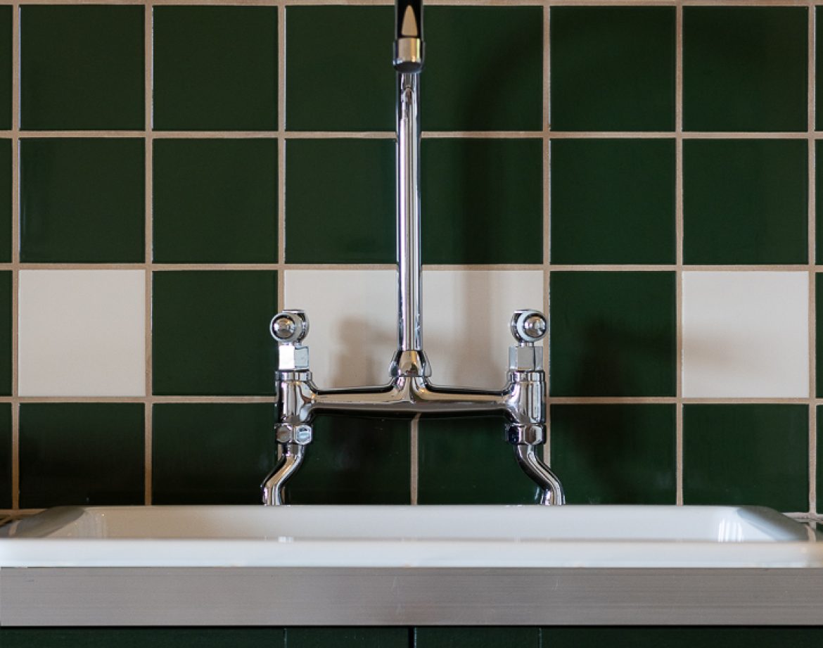 Évier vintage dans un hébergement insolite en Aquitaine, carrelage vert et blanc.