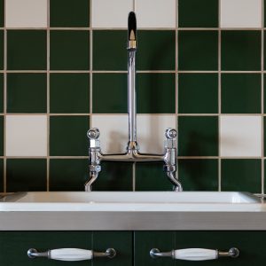 Évier vintage dans un hébergement insolite en Aquitaine, carrelage vert et blanc.