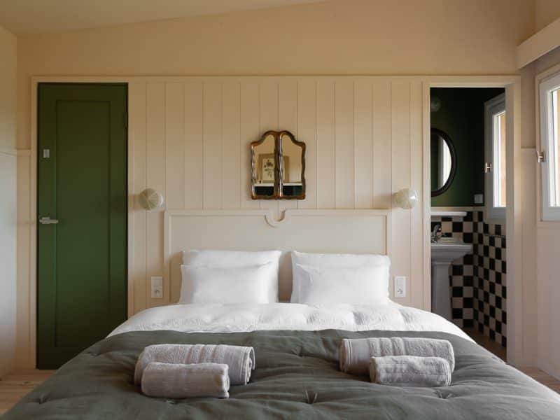 Chambre dhôtes moderne en Aquitaine, avec murs clairs et miroir vintage.