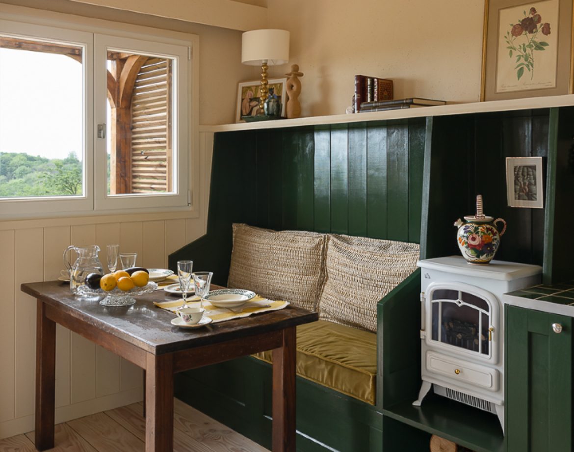 Hébergement insolite en Aquitaine : charmante cabane avec coin repas et poêle à bois.