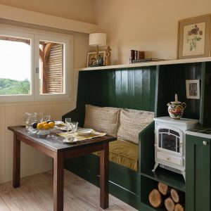 Hébergement insolite en Aquitaine : charmante cabane avec coin repas et poêle à bois.