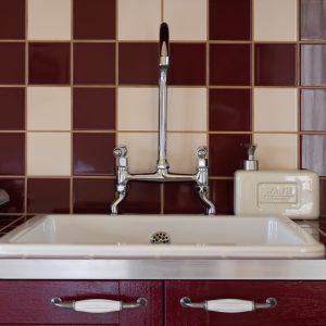 Évier vintage dans un hébergement insolite en Aquitaine, carrelage bicolore élégant.