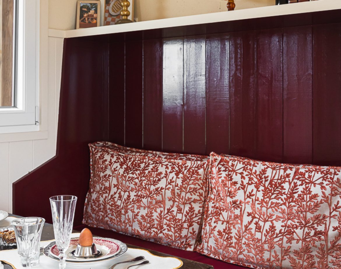 Hébergement insolite en Aquitaine : coin repas cosy avec coussins fleuris et vaisselle élégante.