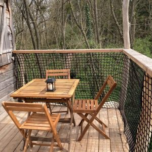 Cabane perchée avec terrasse en bois, vue sur la nature environnante.