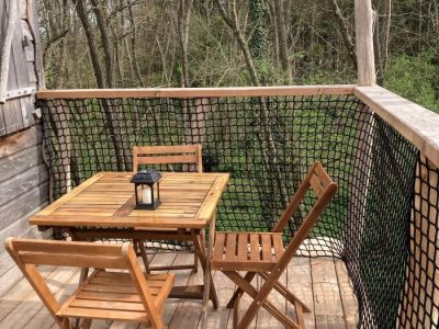 Cabane perchée avec terrasse en bois, vue sur la nature environnante.
