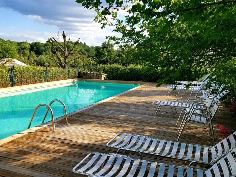 Maison dhôtes avec piscine extérieure entourée de verdure et chaises longues.
