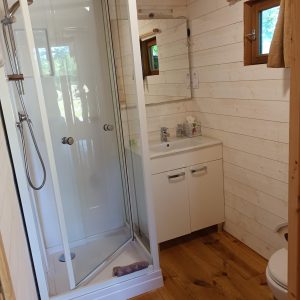 Salle de bain moderne dans un hébergement insolite en bois, avec douche et lavabo.